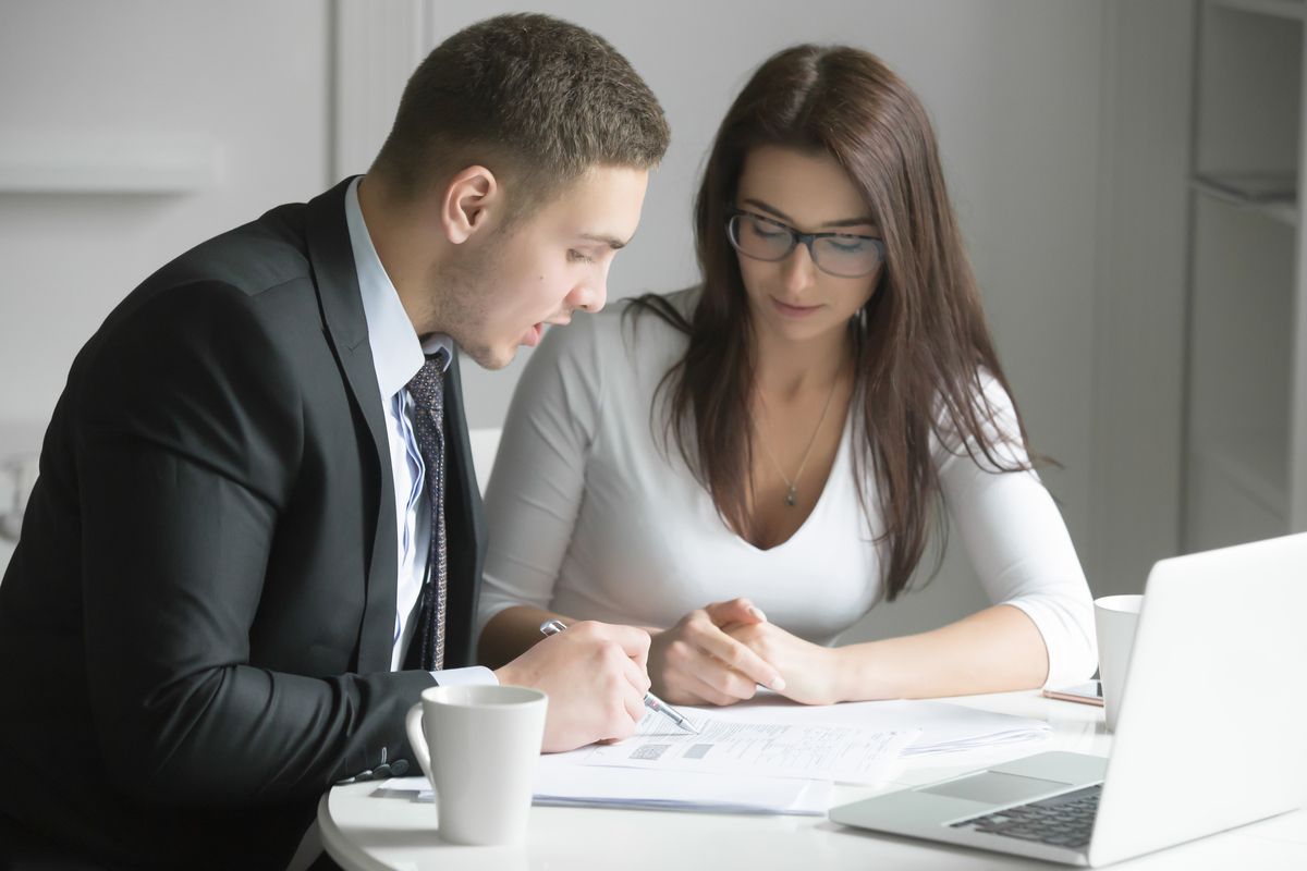 Businessman and businesswoman at office desk, working together w